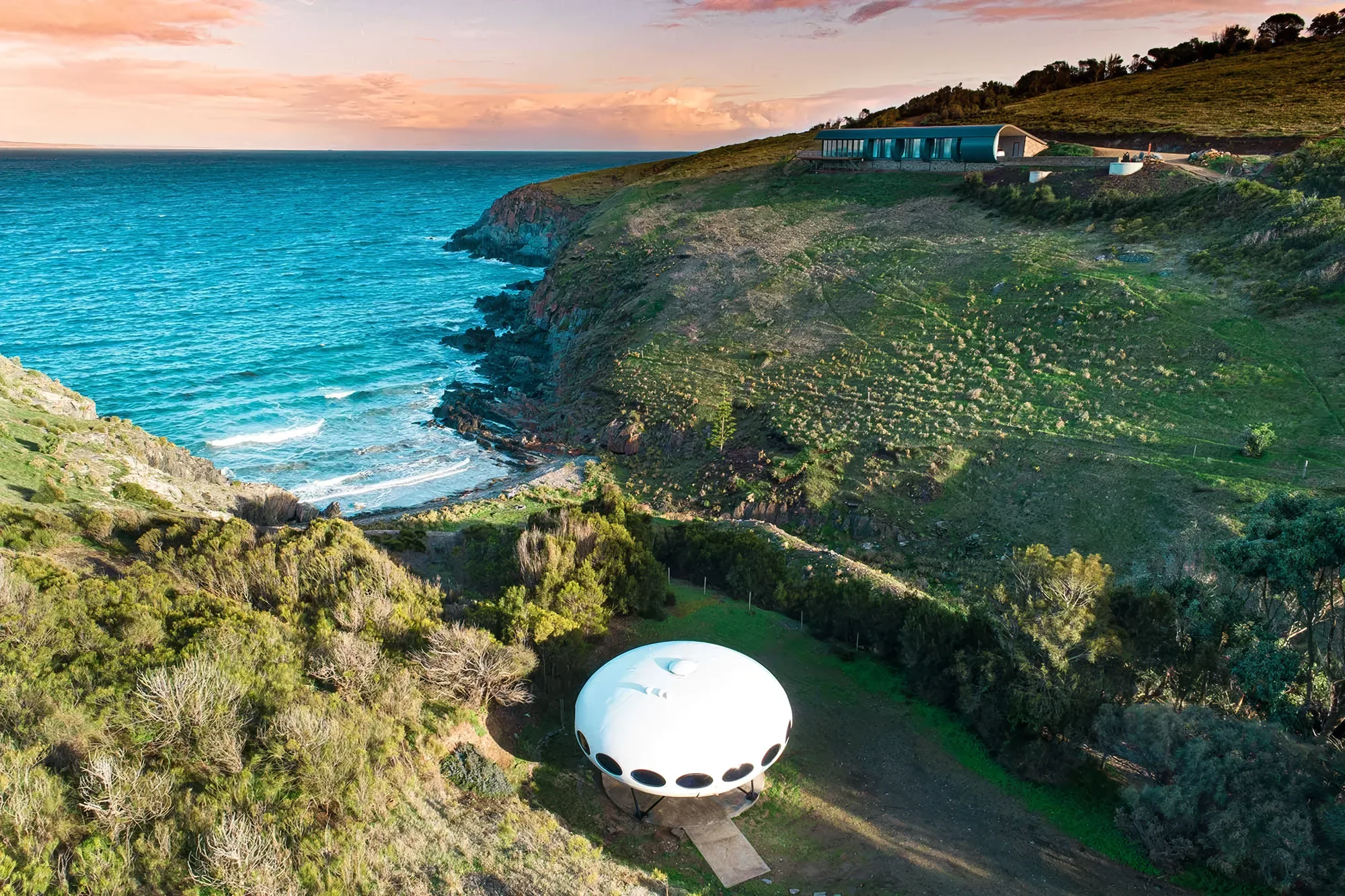 The Futuro house and Naiko Retreat from above, with the coastline and turquoise water beyond