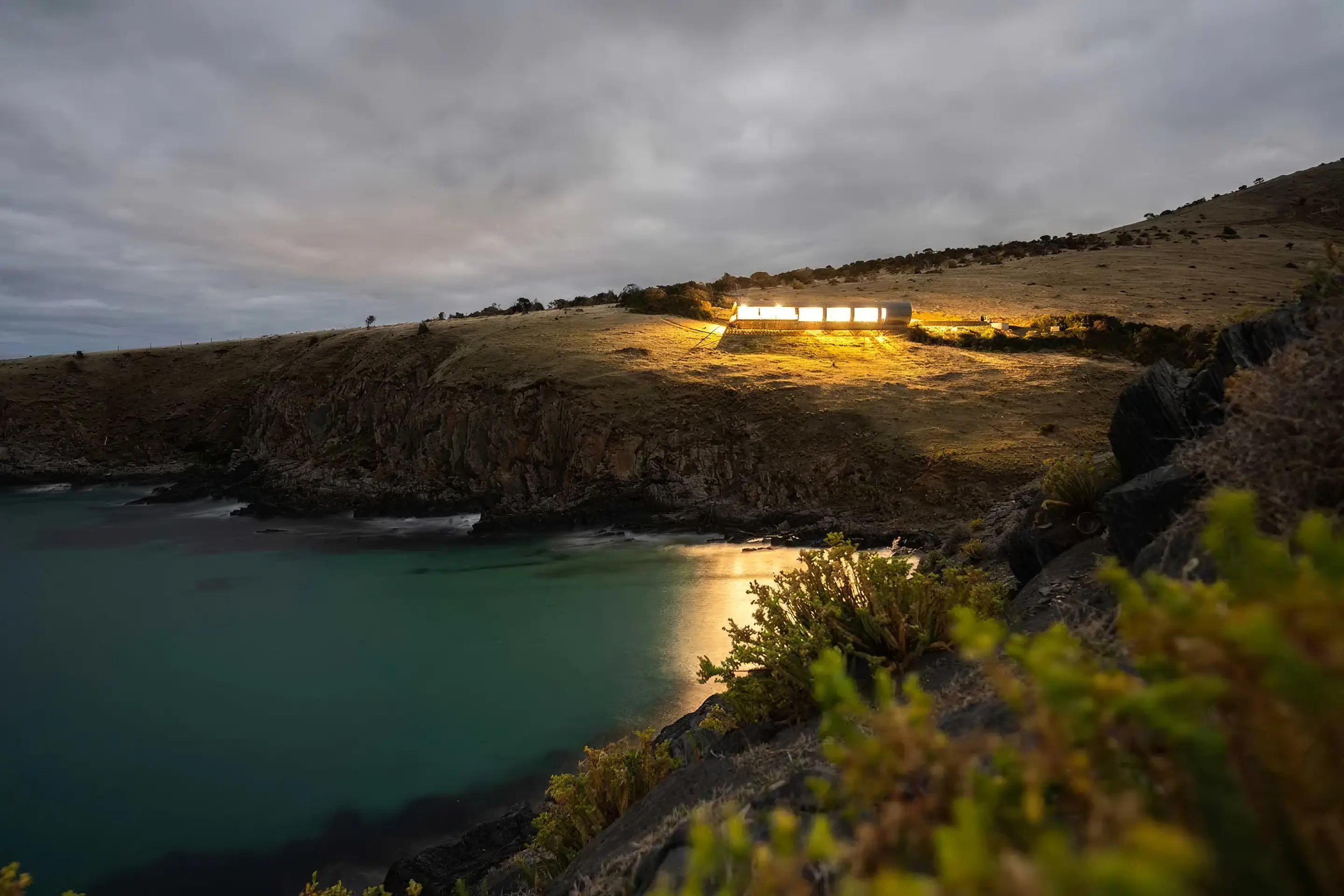 The cove below the retreat at night, lit along the shoreline