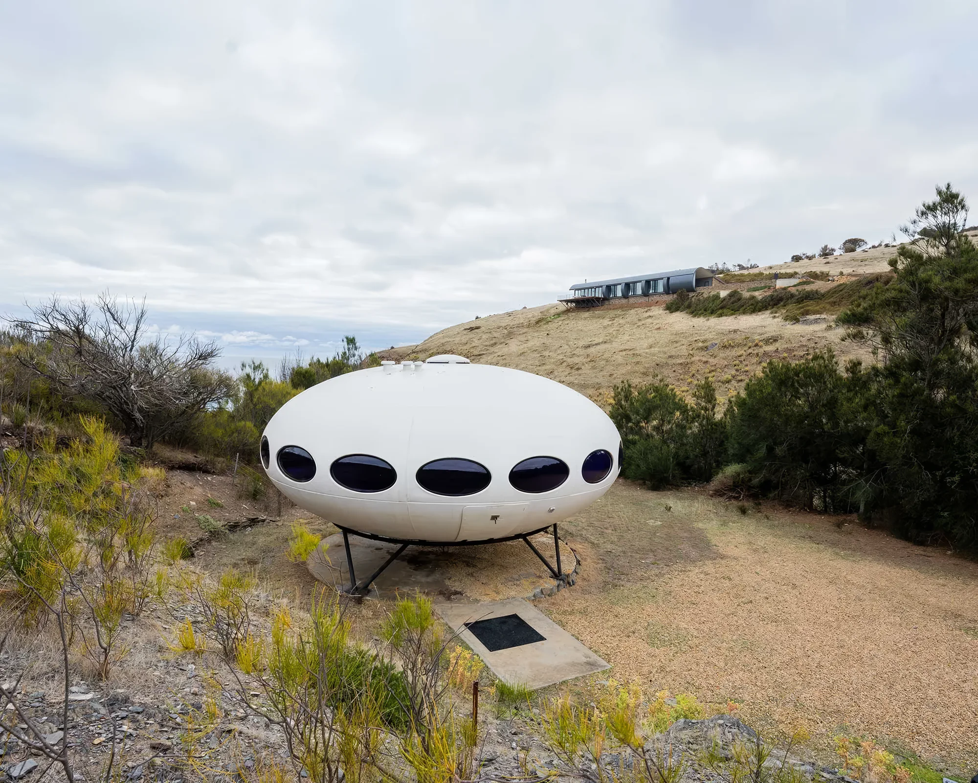 The Futuro in daylight with the hills behind