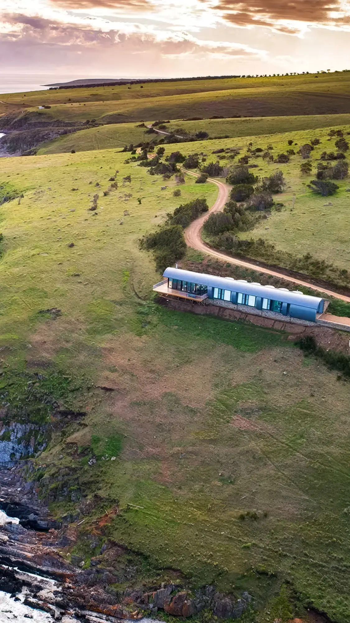 Naiko Retreat at dusk, the long building low on the ridge with the cliff falling to the sea