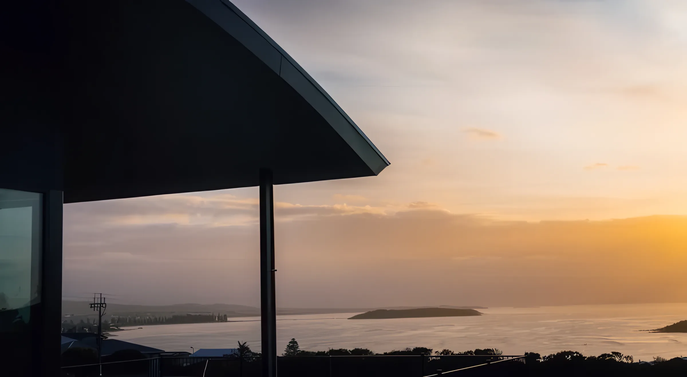 The curved roofline silhouetted against a sunset over the bay